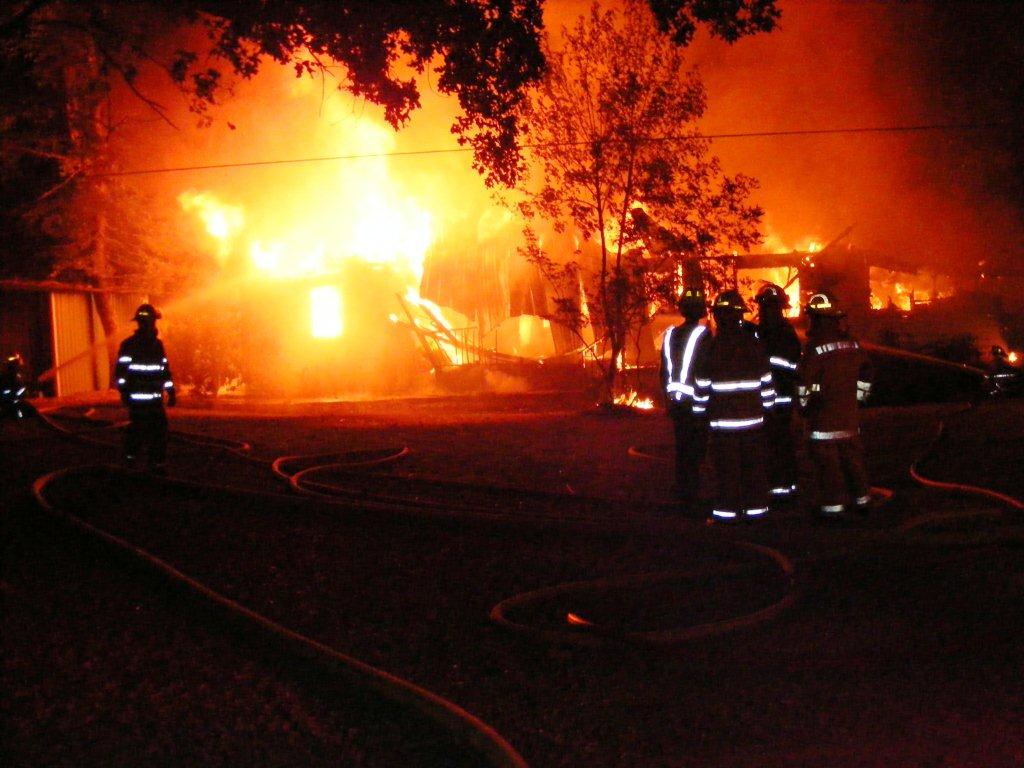 Fire fighters standing in the yard, choosing the best course of action to battle the flames.